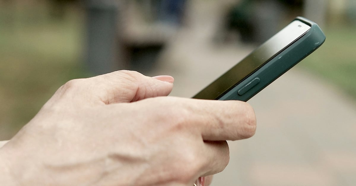 Close view of a hand holding a smartphone side-on, thumb resting on the screen