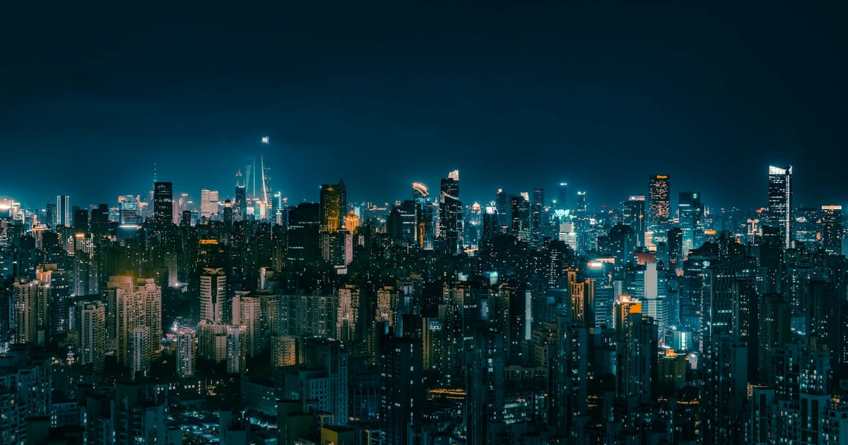 A dense city skyline at night seen from above, thousands of lit windows spread across hundreds of buildings